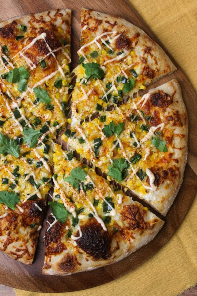 An elote inspired pizza topped with corn and peppers.