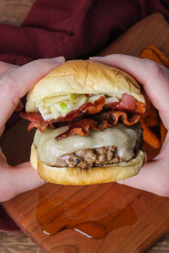 A bacon cheeseburger with maple syrup and apple slaw.