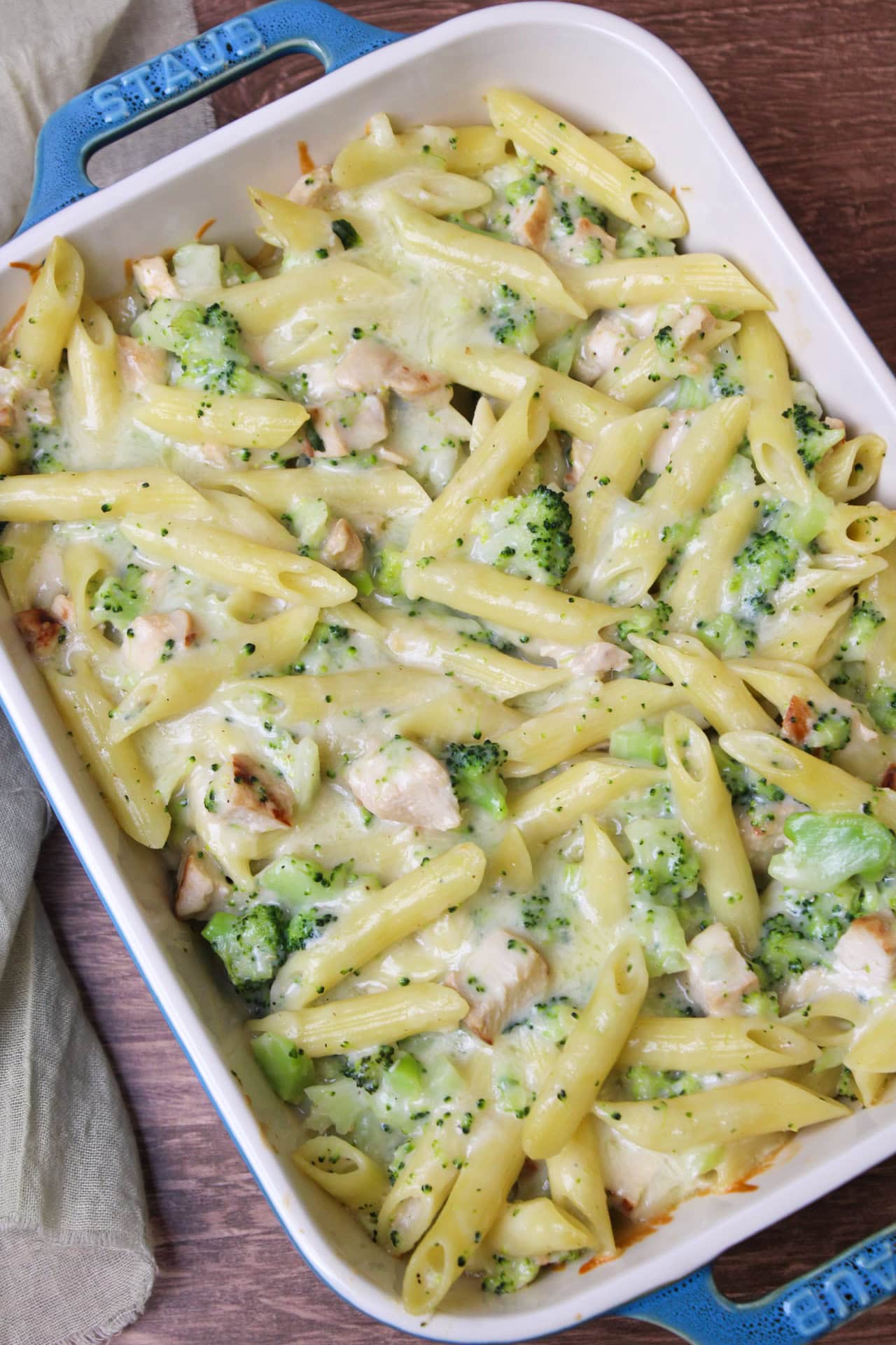Chicken broccoli cheddar pasta bake in a blue ceramic baking dish.