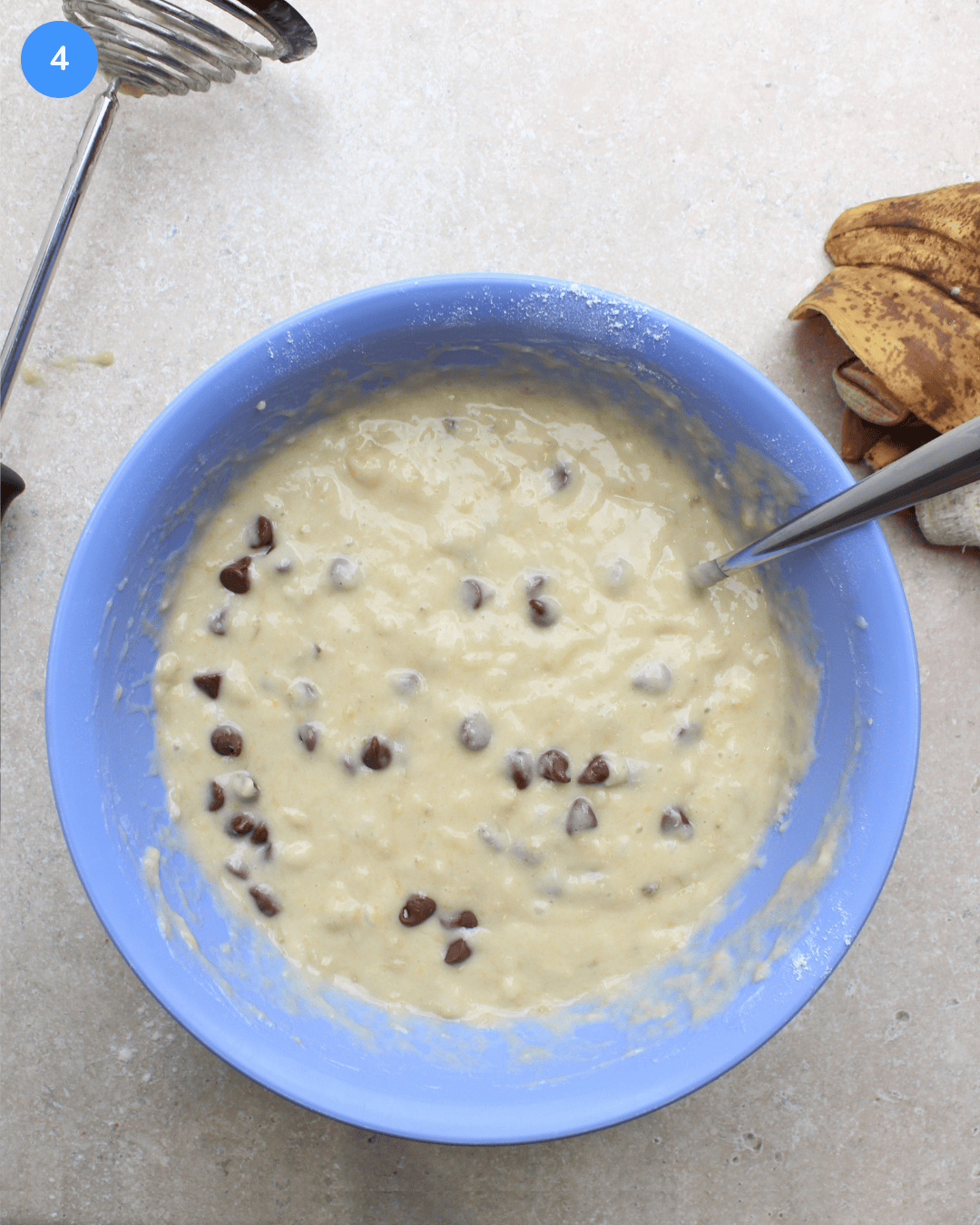 A blue mixing bowl with chocolate chip banana bread batter in it.