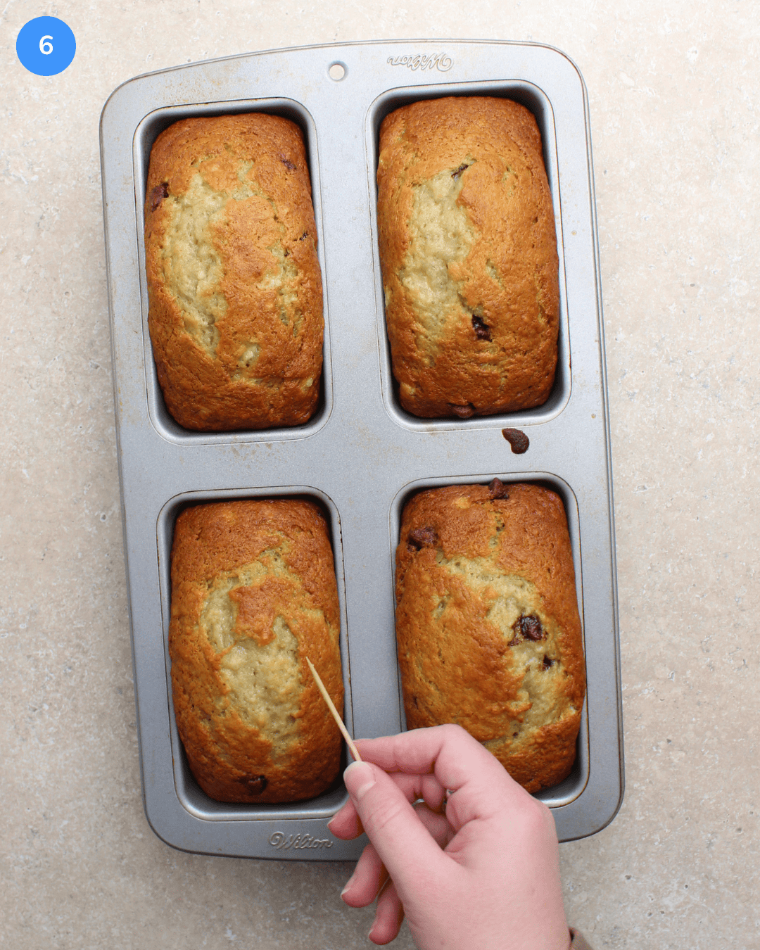 Checking freshly baked banana bread loaves with a toothpick to see if they're done baking.