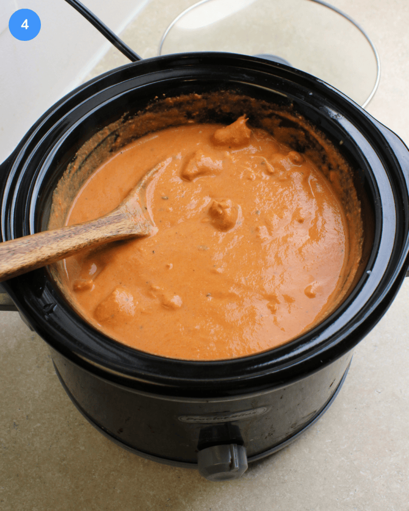 A black slow cooker full of freshly made chicken tikka masala.