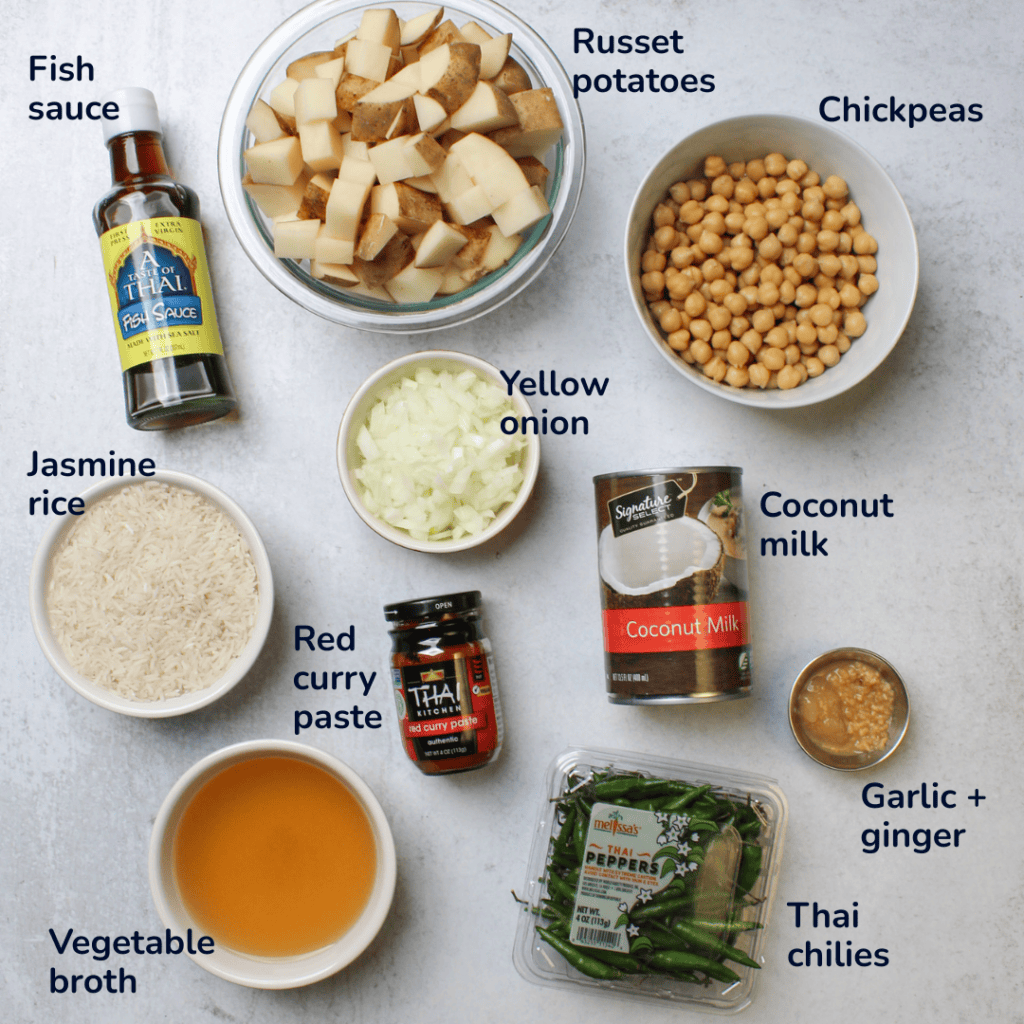 Ingredients for Thai chickpea potato curry: russet potatoes, chickpeas, fish sauce, yellow onion, coconut milk, garlic and ginger, red curry paste, jasmine rice, vegetable broth, and green Thai chilies.