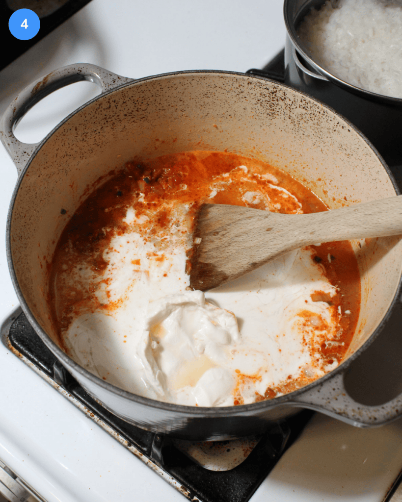A gray ceramic dutch oven with coconut milk, vegetable broth, fish sauce, and curry paste in it.