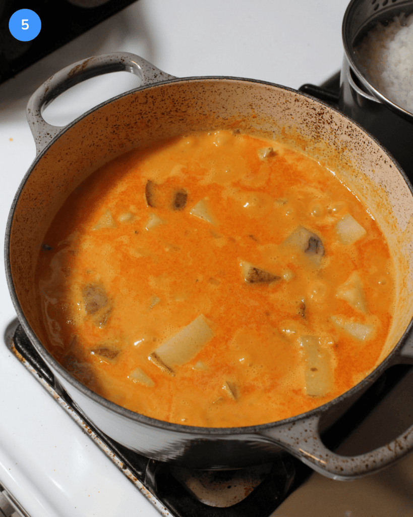 A pot of red potato and chickpea Thai curry simmering on the stove.