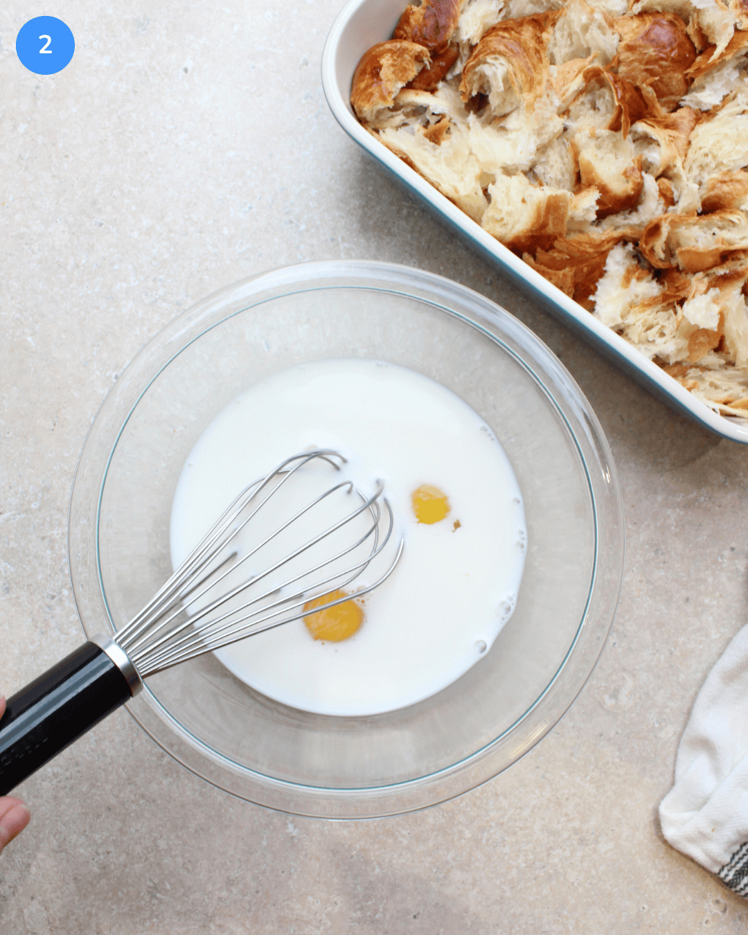 A bowl of milk and eggs right before being whisked.