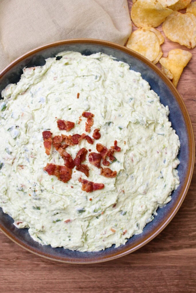 Cold jalapeno popper dip with bacon in a blue stoneware bowl.