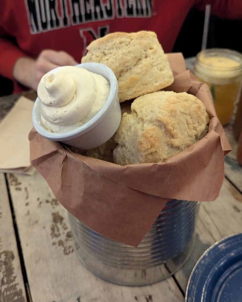 A bucket of giant biscuits and honey butter.