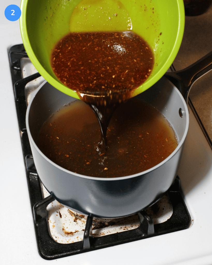 A soy sauce, vinegar, and chili oil sauce being poured into a saucepan with chicken and vegetable broth.