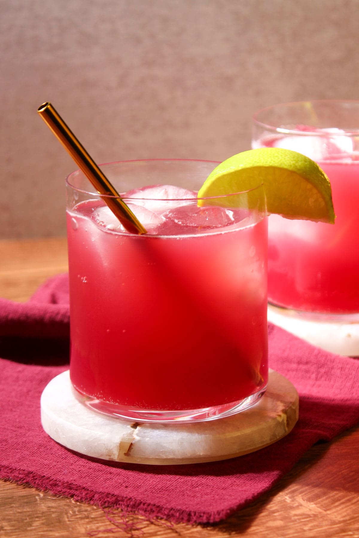 A rocks glass with a pomegranate mule mocktail in it, garnished with a lime wedge.