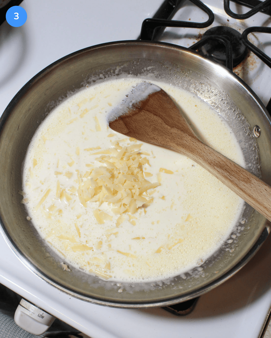 A stainless steel pan with heavy cream and shredded parmesan in it.