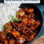 Saucy, spicy General Tso's chicken served with white rice in a black bowl.