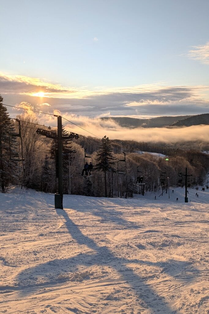 A ski mountain chairlift scene at sunset.