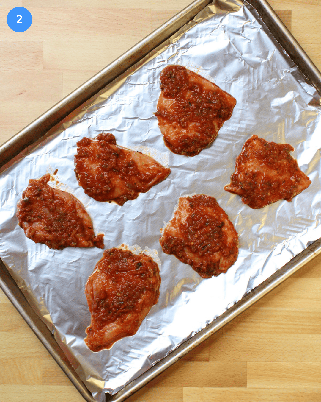 Salsa marinated chicken breast on a foil-lined baking sheet before going into the oven.