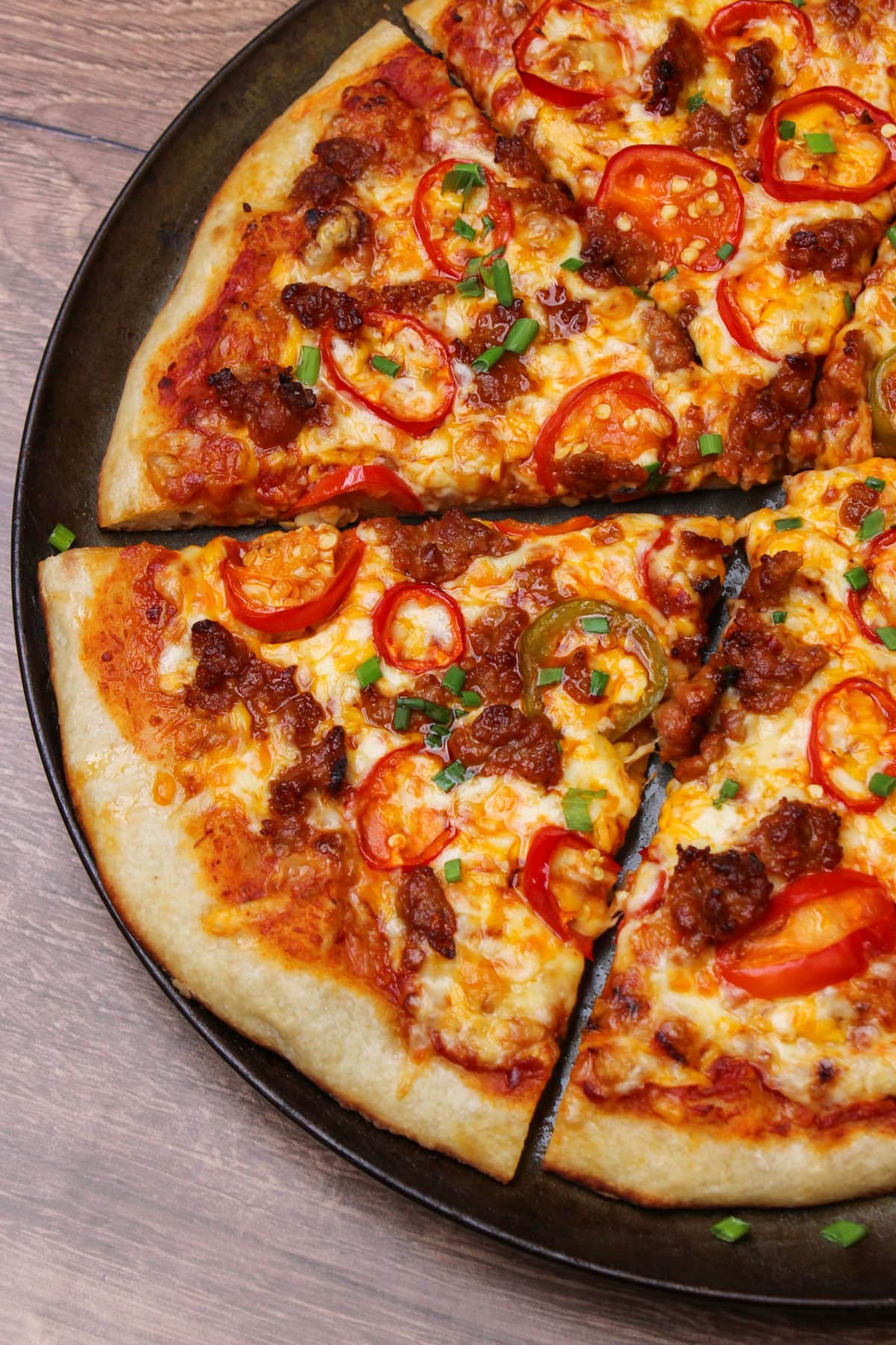 A perfectly cooked slice of spicy sausage and pepper pizza on a round pizza pan.