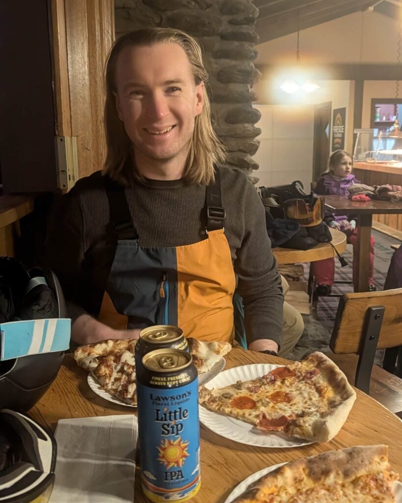 Alex in a ski lodge eating pizza.