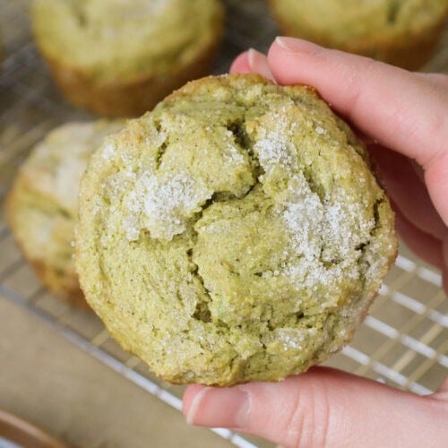 A hand holding a freshly baked avocado muffin.