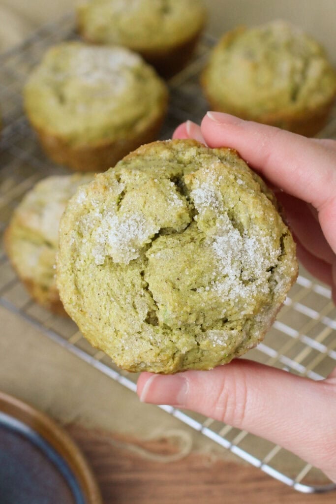 A hand holding a freshly baked avocado muffin.