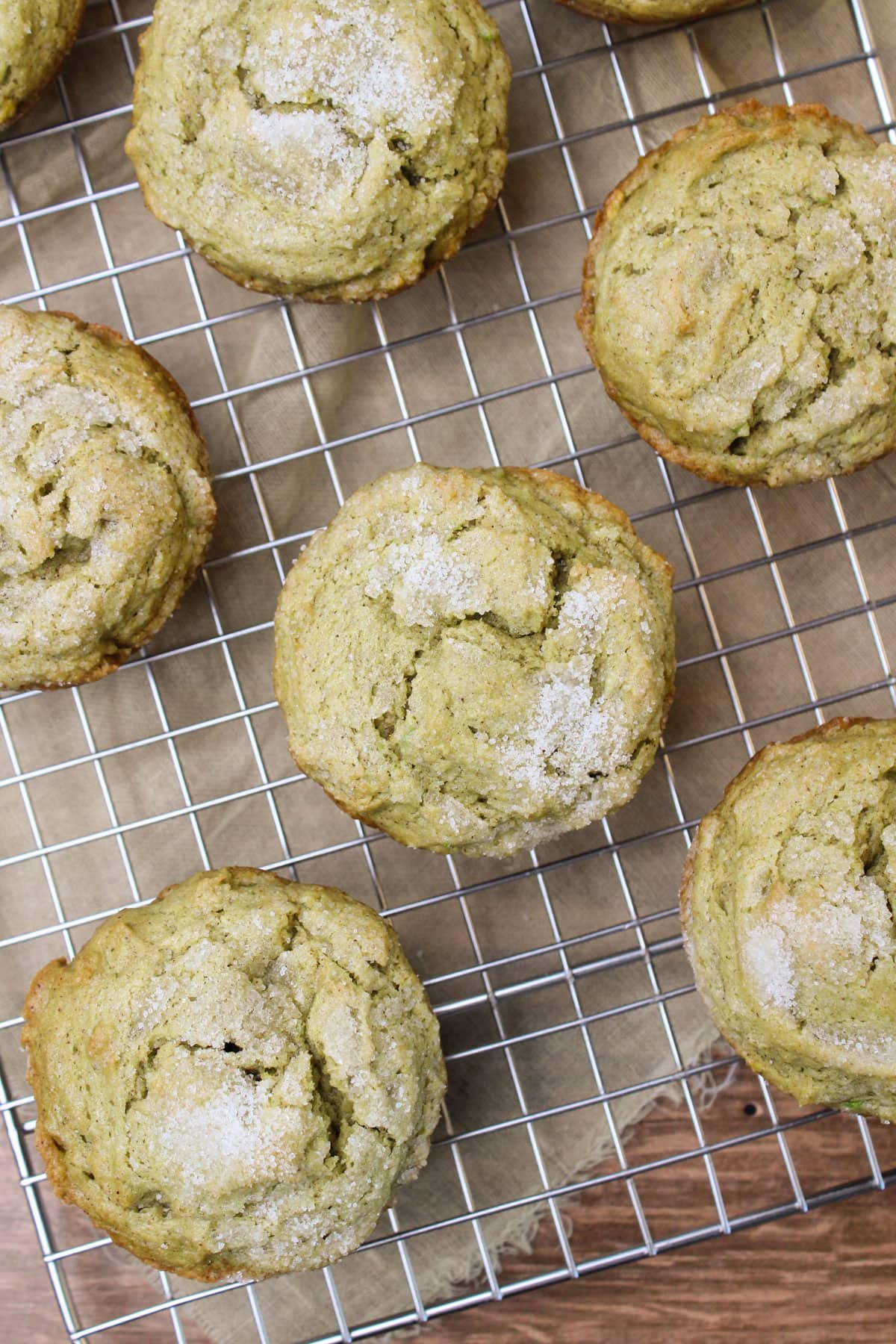 Fresh cinnamon avocado muffins sprinkled with sugar on a wire cooling rack.