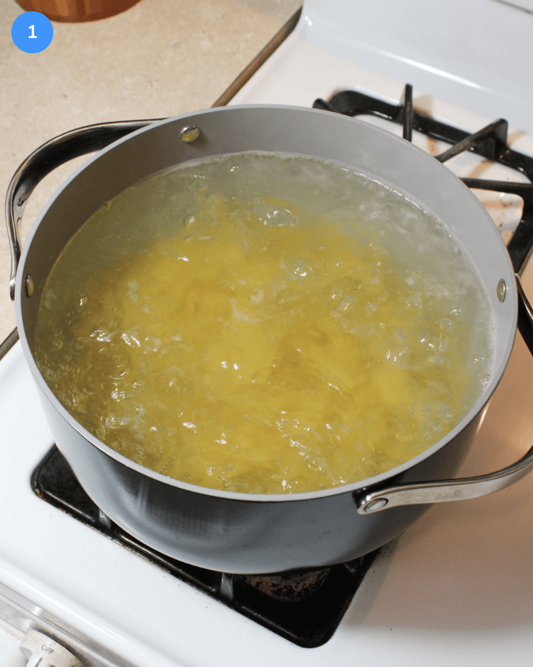 Penne pasta boiling in a ceramic pot on the stove.