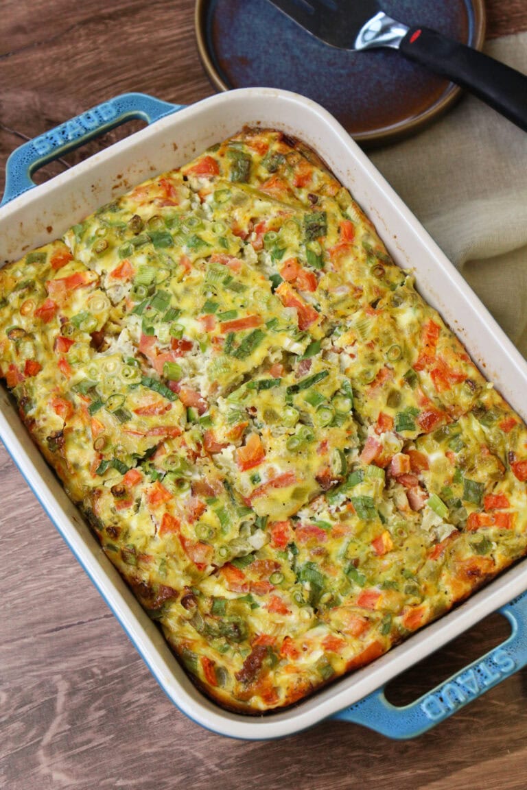 A rectangular baking dish with freshly baked green chili egg casserole in it, sliced into squares for serving.