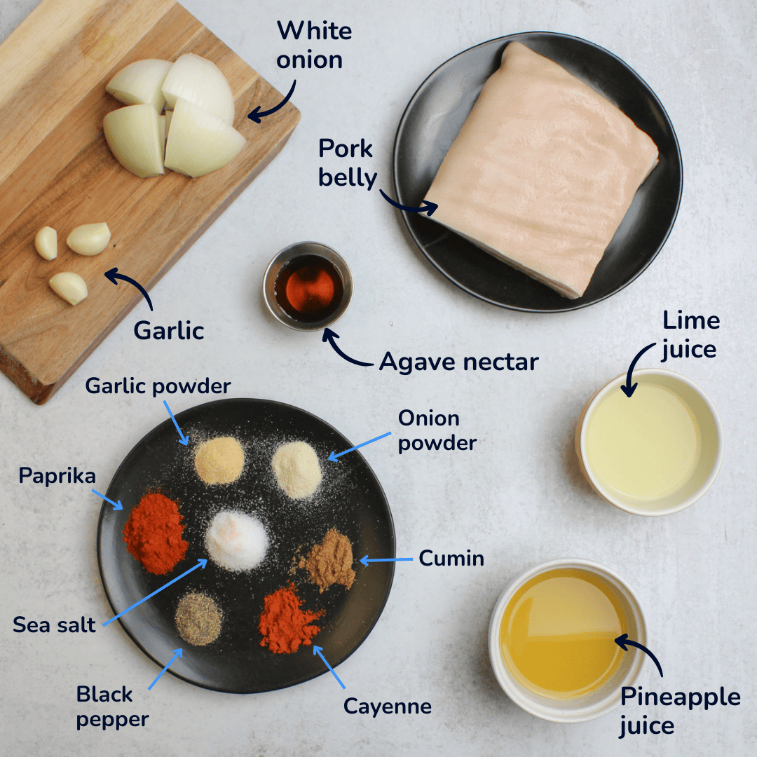 Ingredients for making slow cooker pork belly: pork belly, white onion, garlic, agave nectar, lime juice, pineapple juice, garlic powder, onion powder, cumin, cayenne, black pepper, sea salt, and paprika.