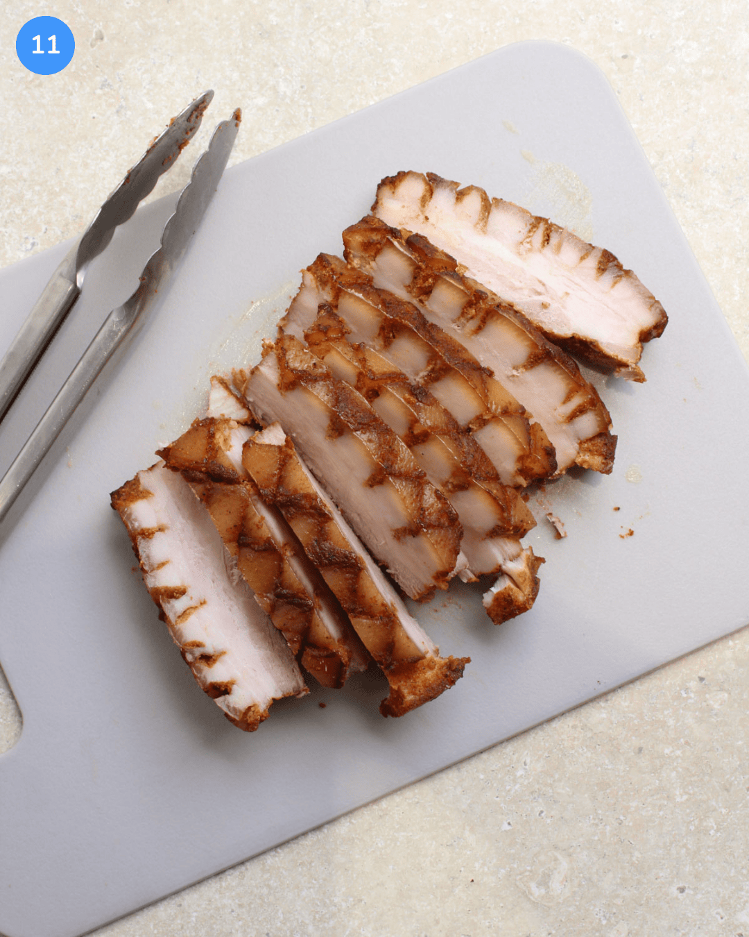 Slabs of chilled slow cooker pork belly on a cutting board after being sliced.