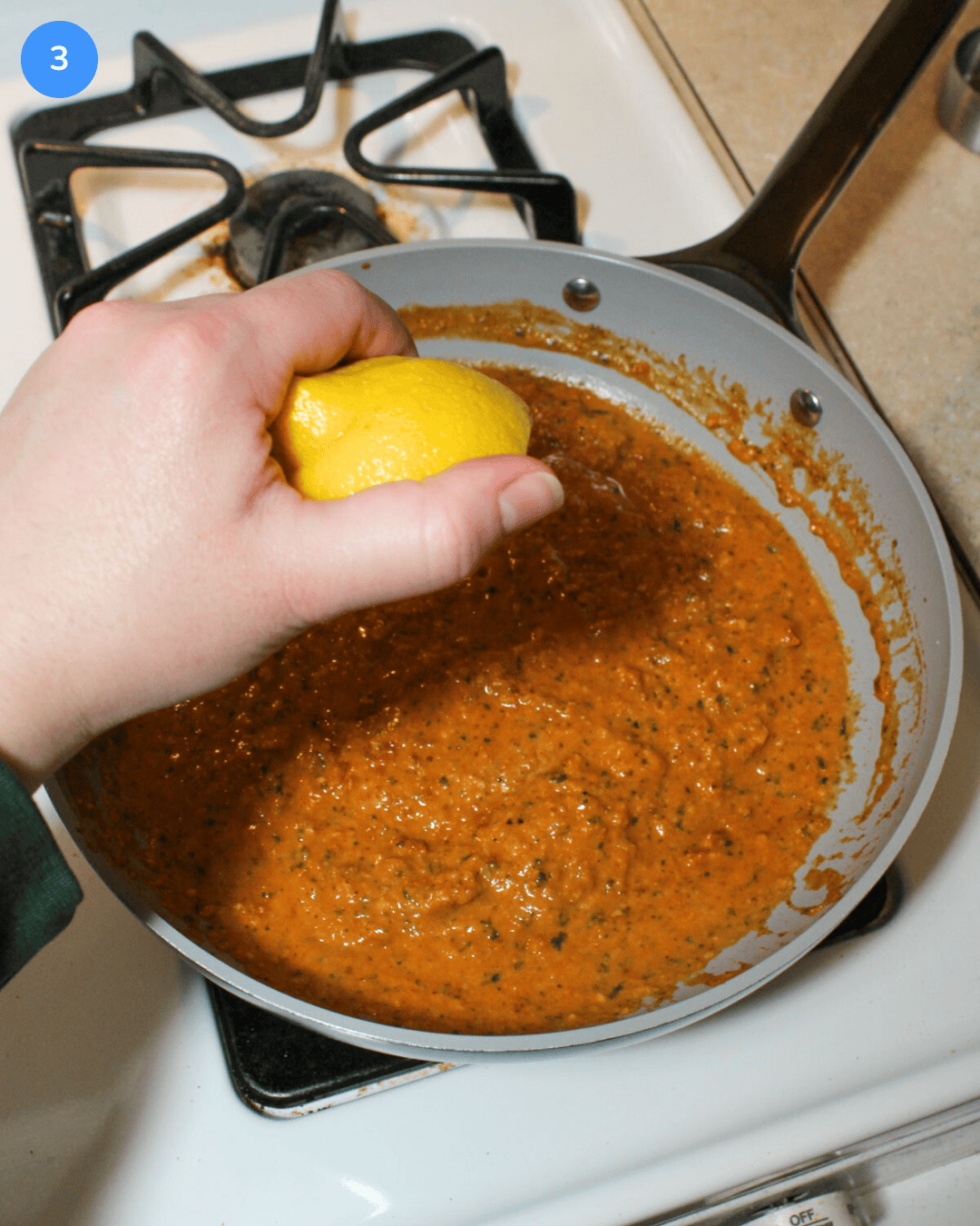 Squeezing fresh lemon juice into a frying pan full of sun dried tomato pesto pasta sauce.