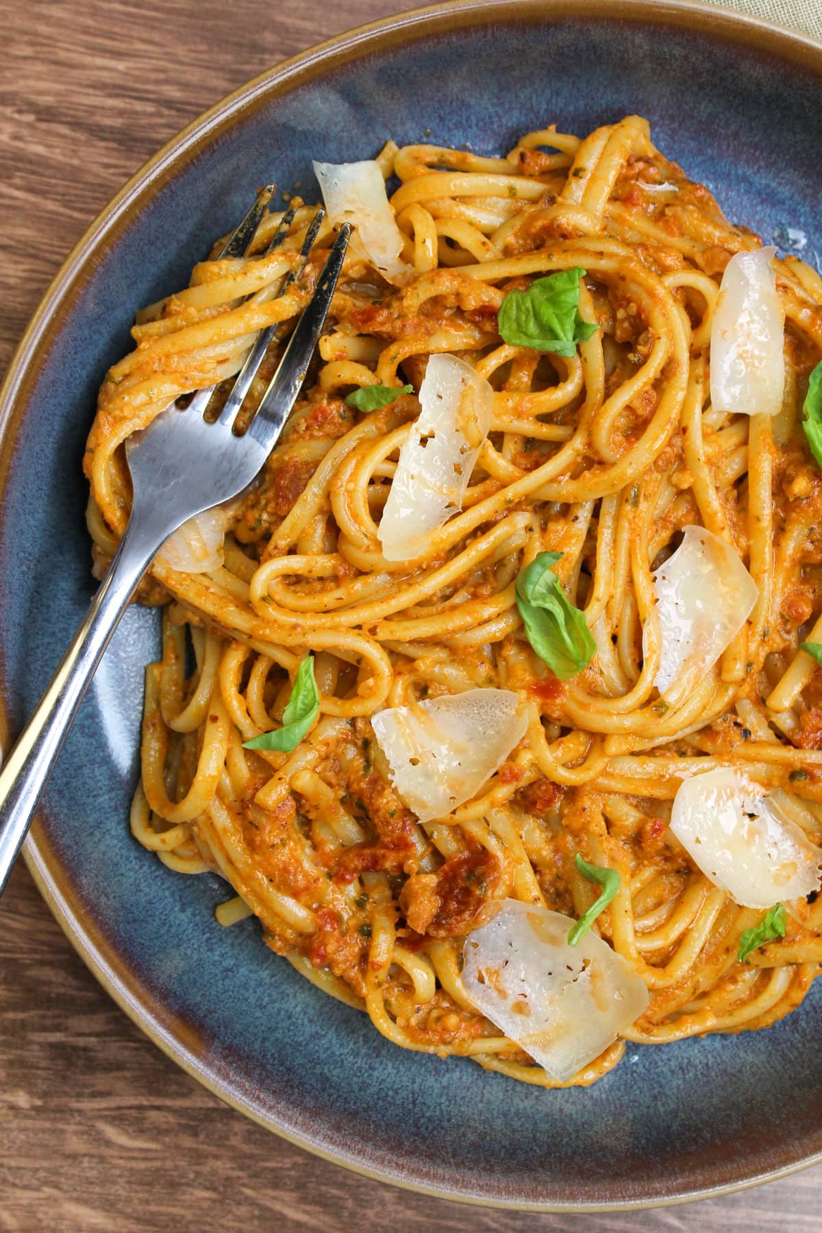 A bowl of creamy sun dried tomato pesto pasta with parmesan and fresh basil.