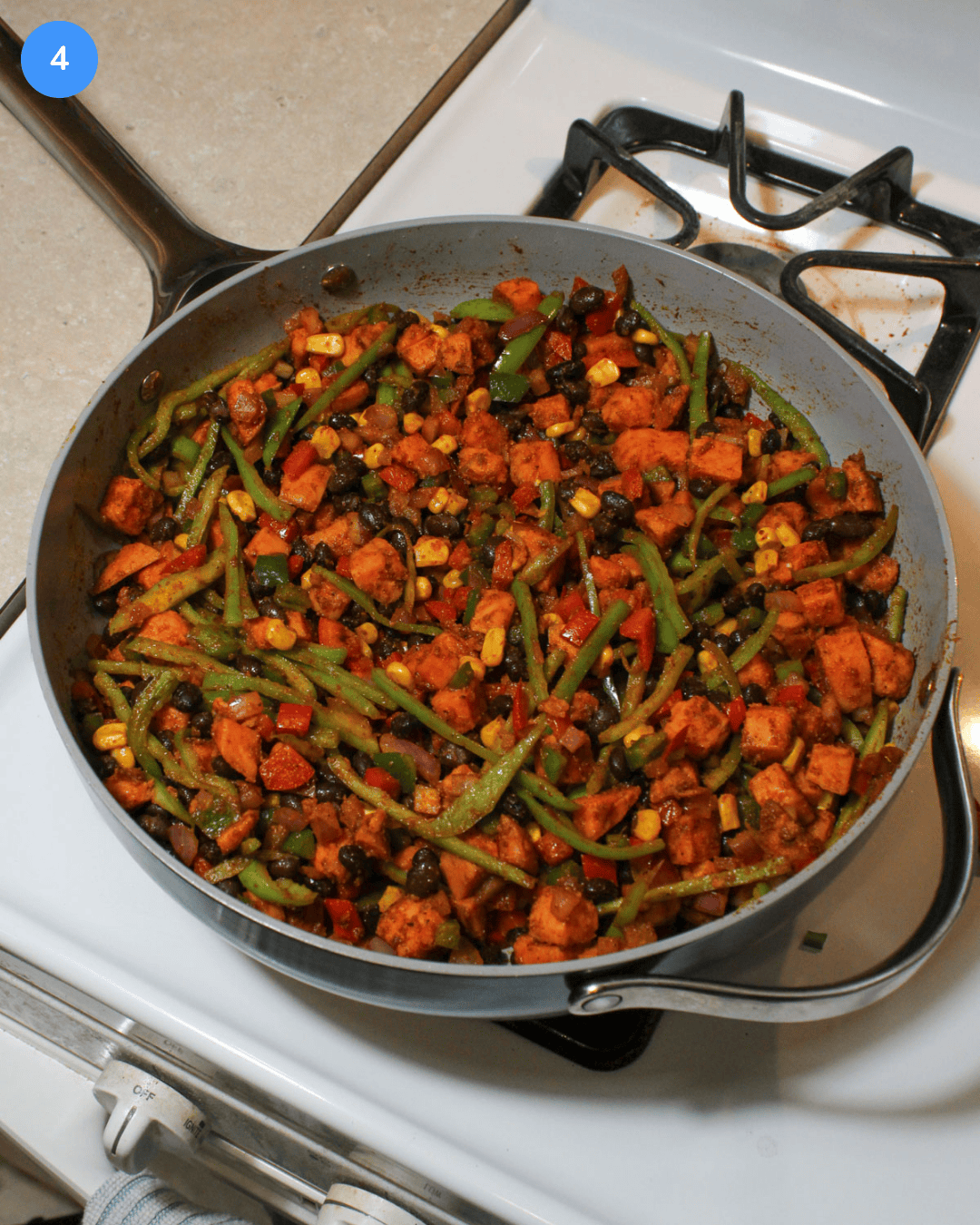A large ceramic saute pan filled with freshly cooked sweet potato taco bowl filling.