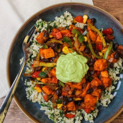 A freshly made sweet potato taco bowl with a dollop of avocado lime crema on top.