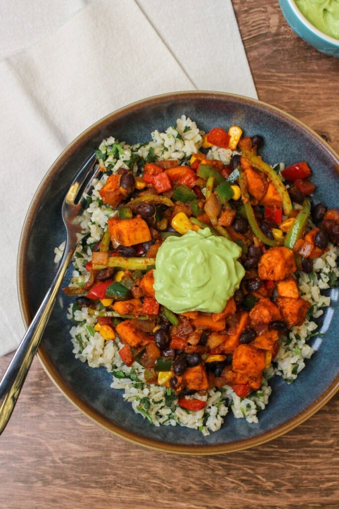 A freshly made sweet potato taco bowl with a dollop of avocado lime crema on top.