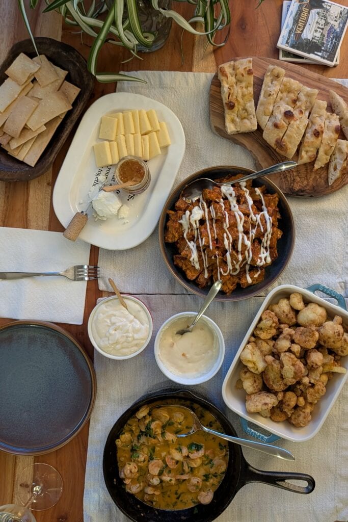 A tapas spread on a wooden table with ivory placemats.
