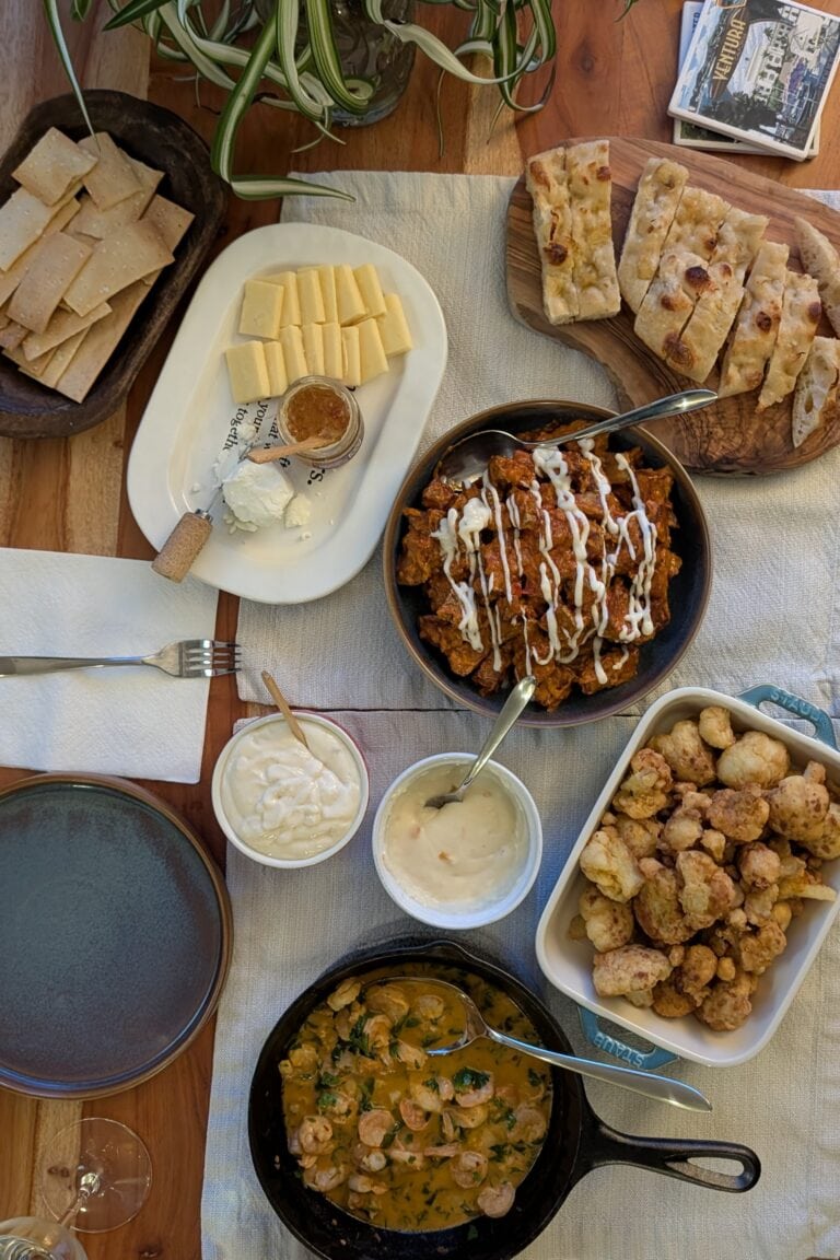 A tapas spread on a wooden table with ivory placemats.