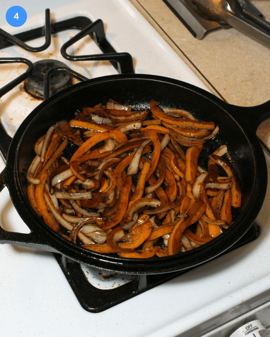 A cast iron skillet of freshly cooked peppers and onions after being seasoned with lime juice and salt.