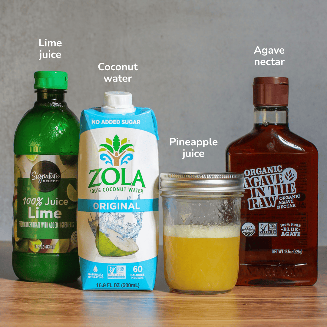 Ingredients for a pineapple coconut mocktail: lime juice, coconut water, pineapple juice, and agave nectar.