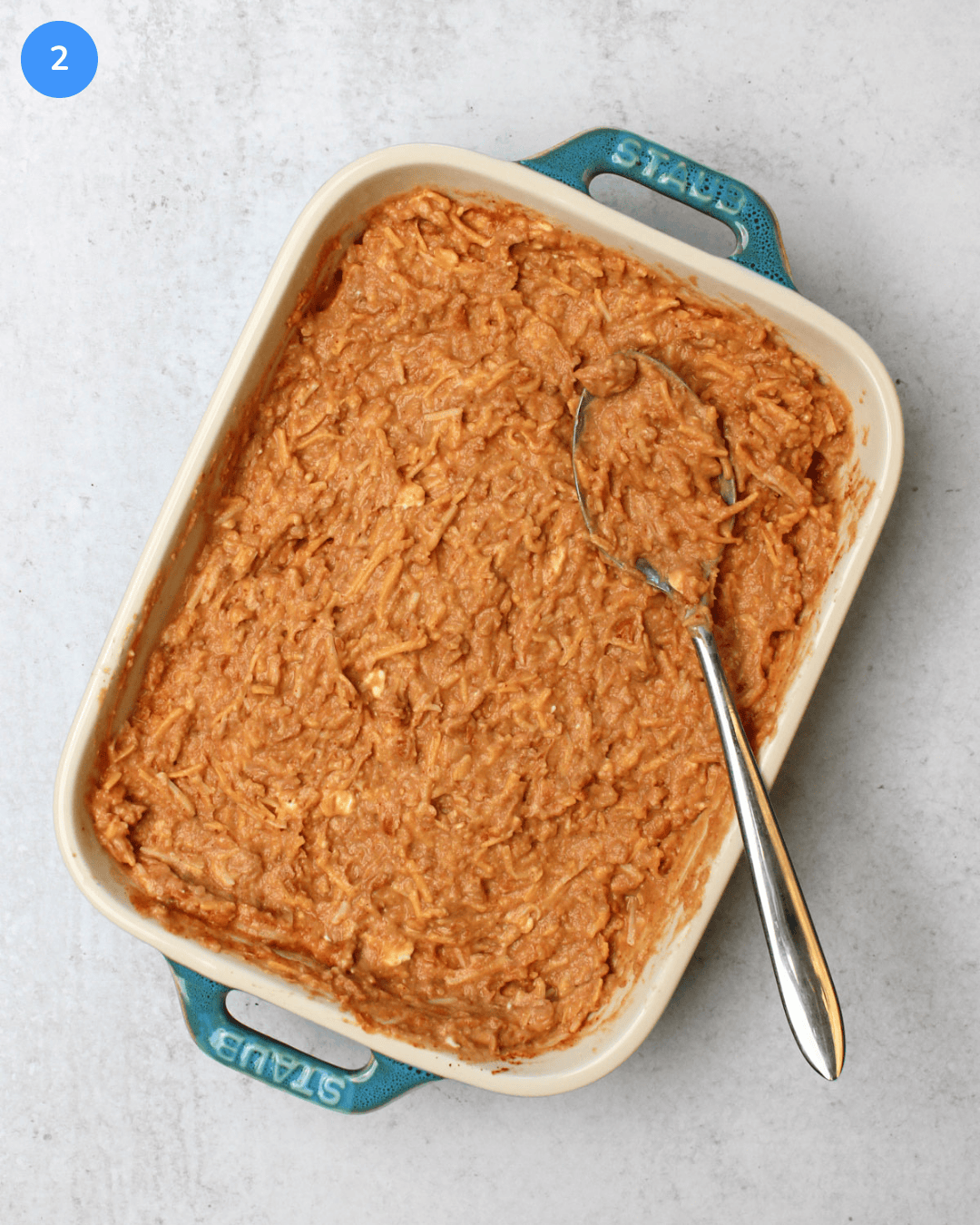 A small ceramic baking dish with refried bean dip mixed in it, before baking.