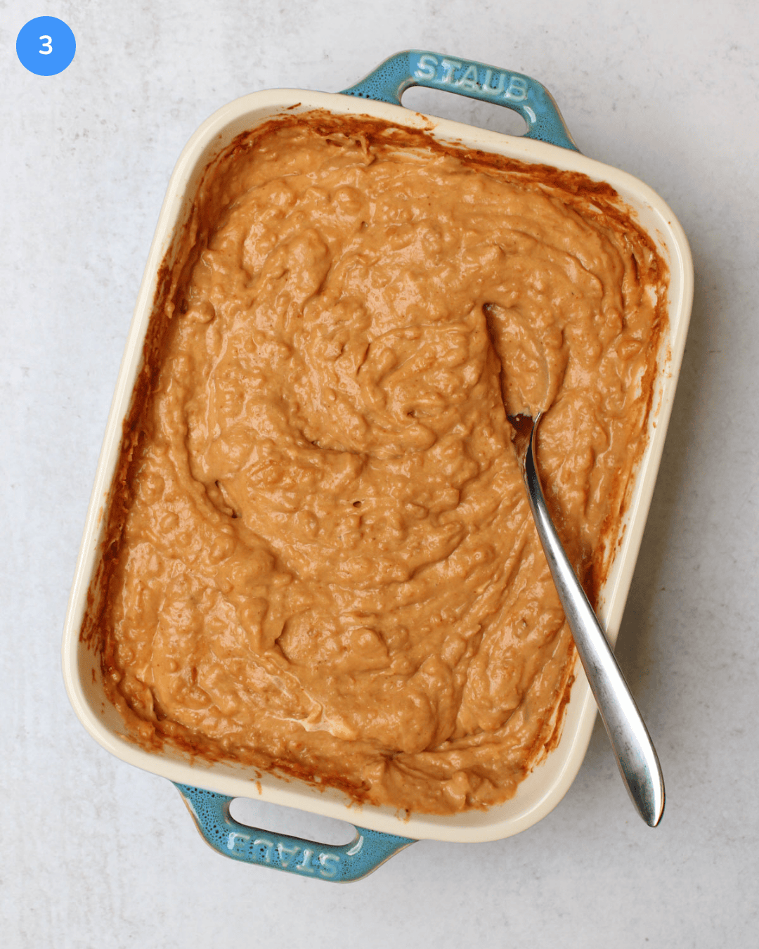 A small ceramic baking dish of a creamy, freshly baked Mexican bean dip.