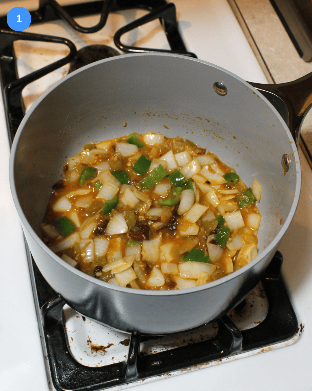 Diced veggies cooking in a small ceramic saucepan on the stove.