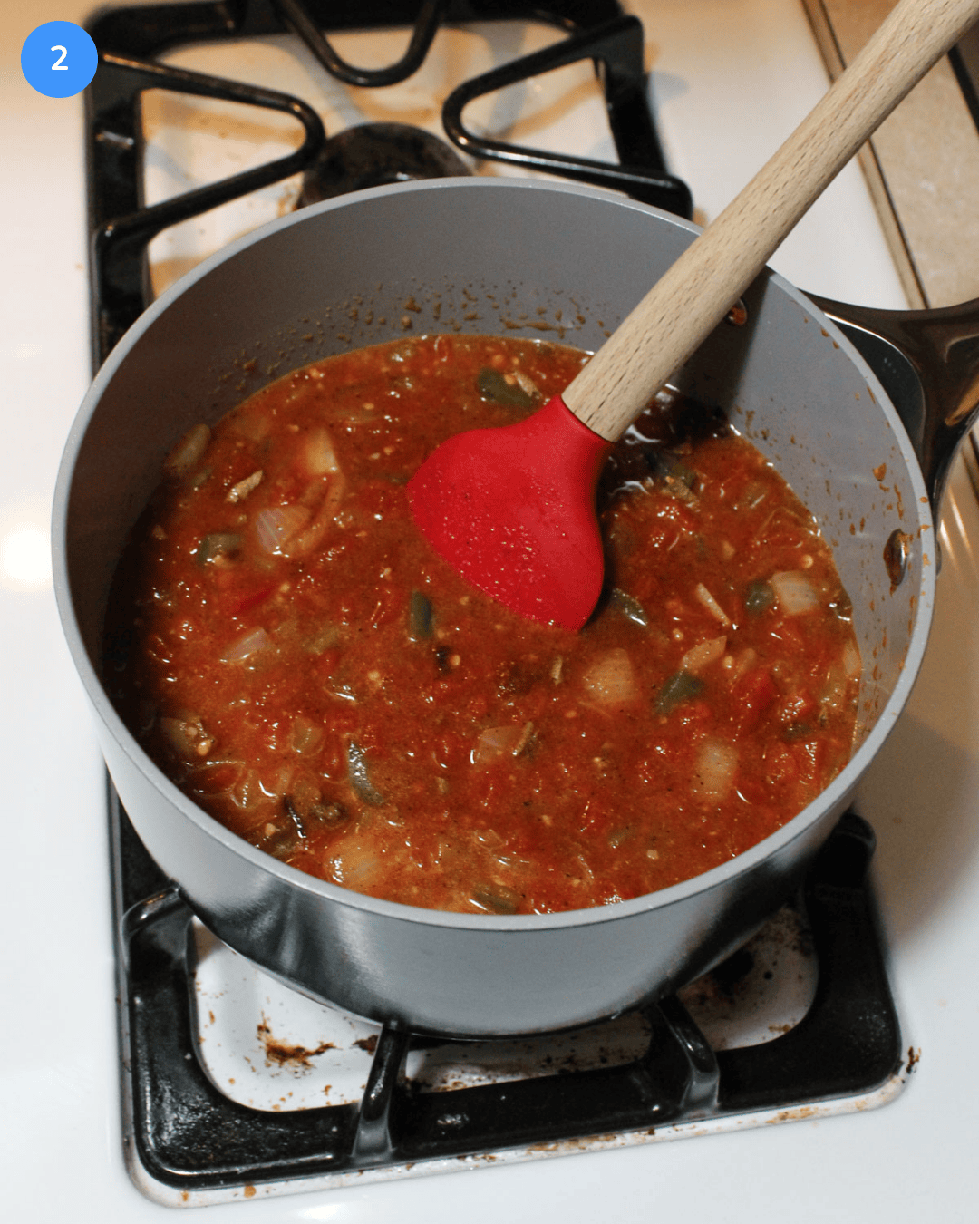 A small ceramic saucepot filled with diced veggies, tomatoes, and broth.