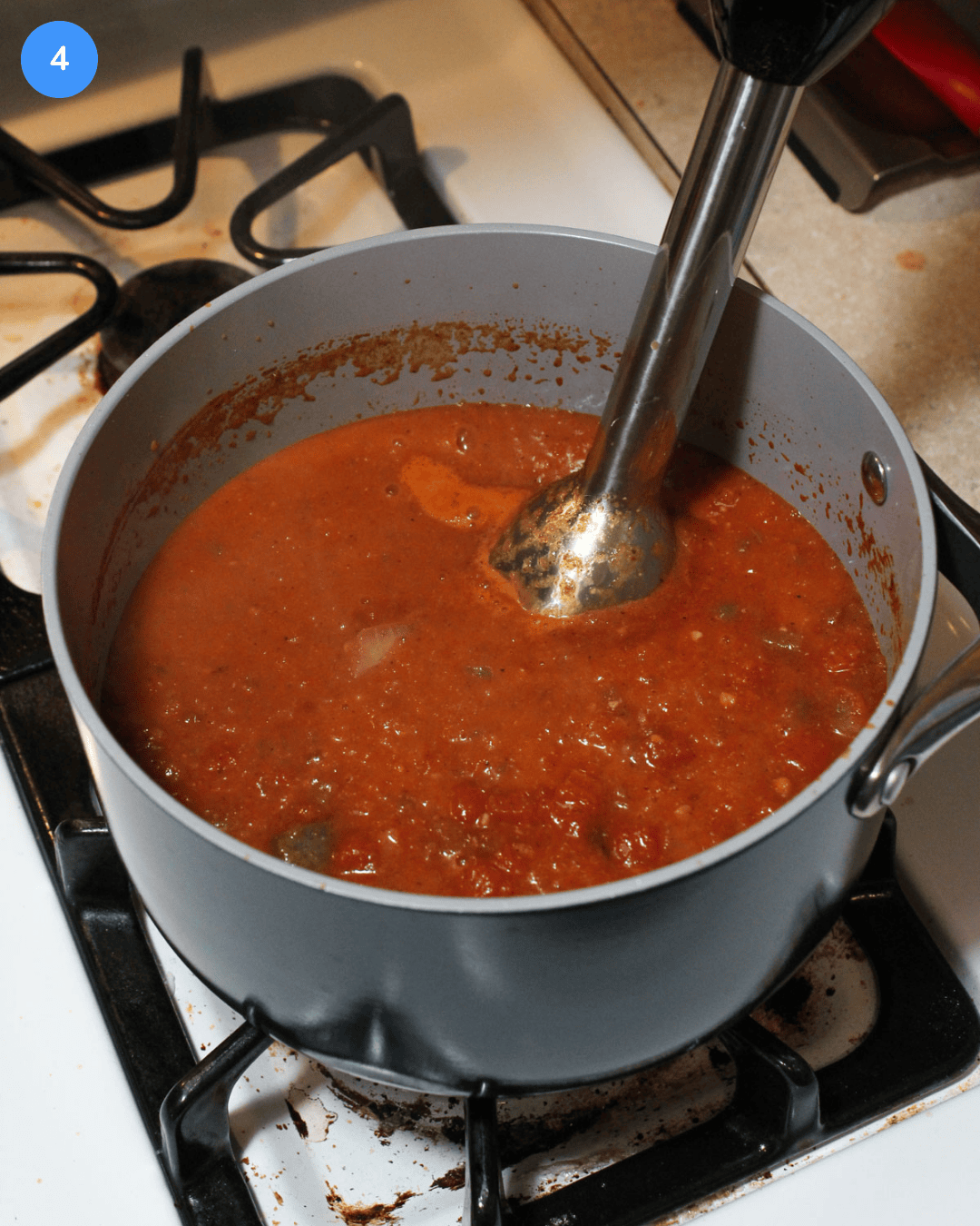 A pot of freshly simmered ranchero sauce being blended with an immersion blender.