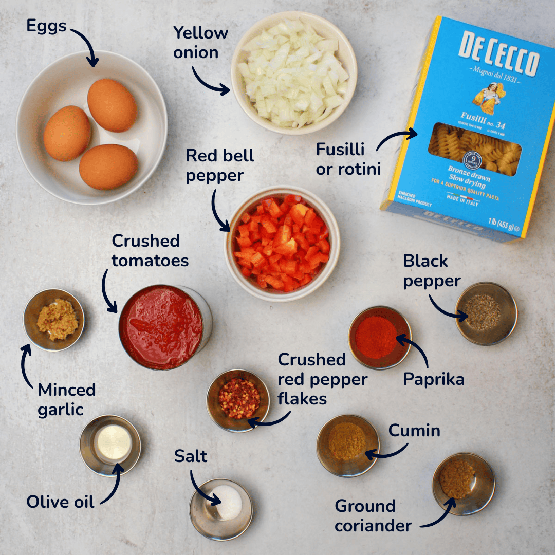 Ingredients for making shakshuka pasta: eggs, yellow onion, fusilli or rotini pasta, red bell pepper, crushed tomatoes, minced garlic, olive oil, salt, crushed red pepper flakes, ground coriander, cumin, paprika, and black pepper.