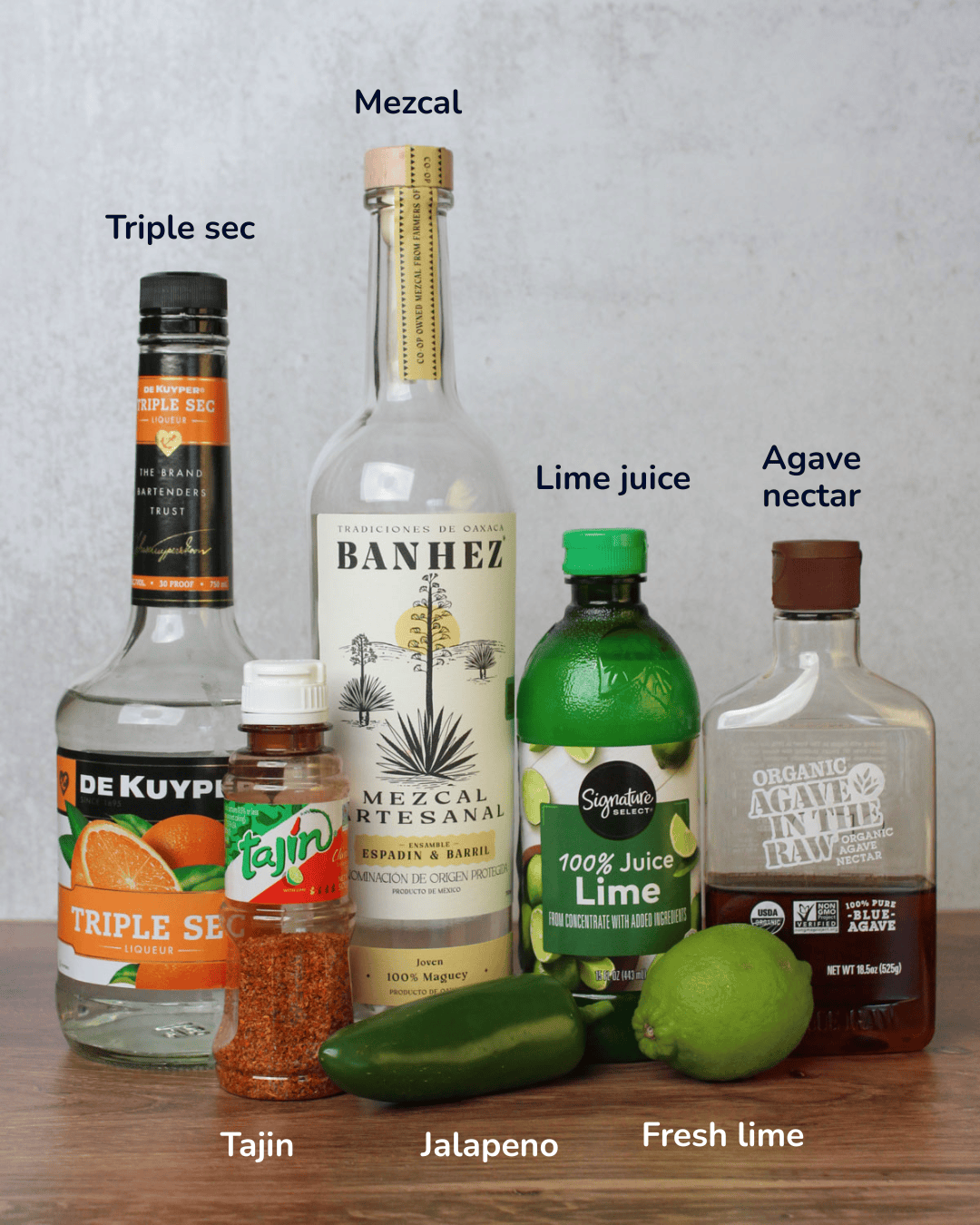 Ingredients for a spicy mezcal margarita: mezcal, triple sec, lime juice, agave nectar, Tajin, jalapeno, and fresh lime.