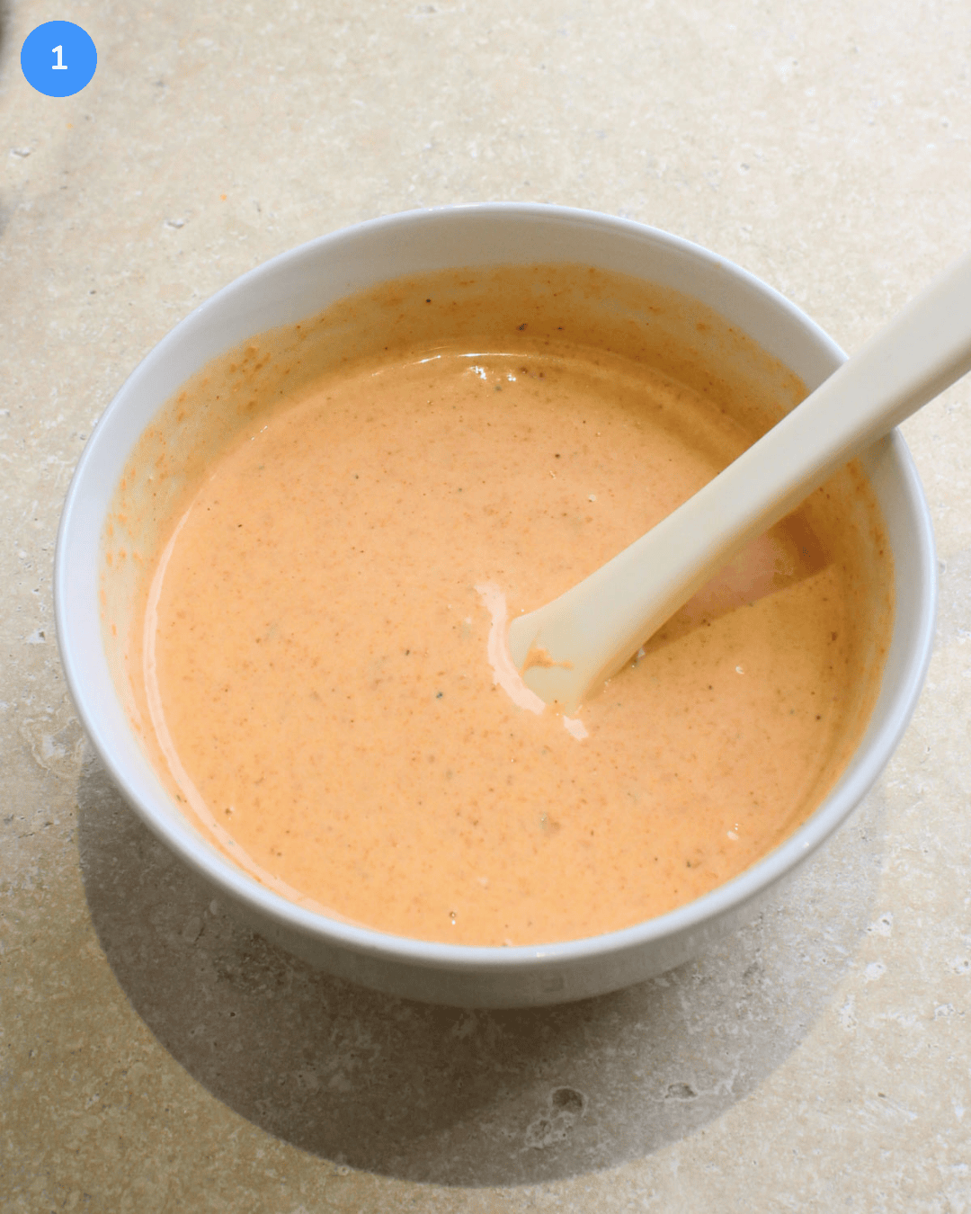 A small white bowl of spicy ranch sauce.