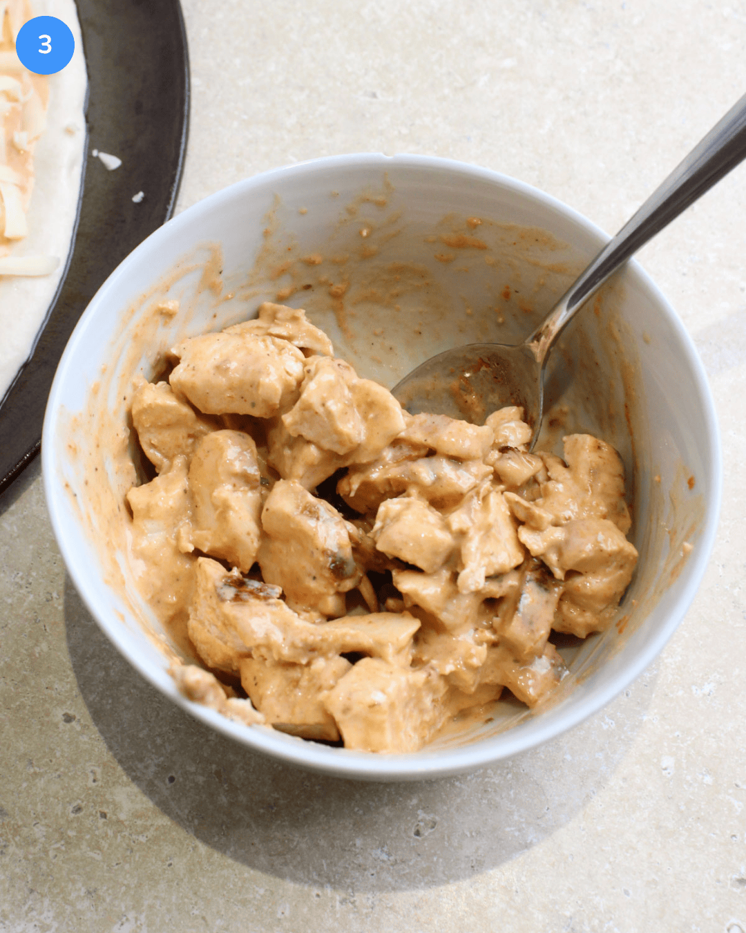 A small white bowl with diced grilled chicken tossed in spicy ranch sauce.