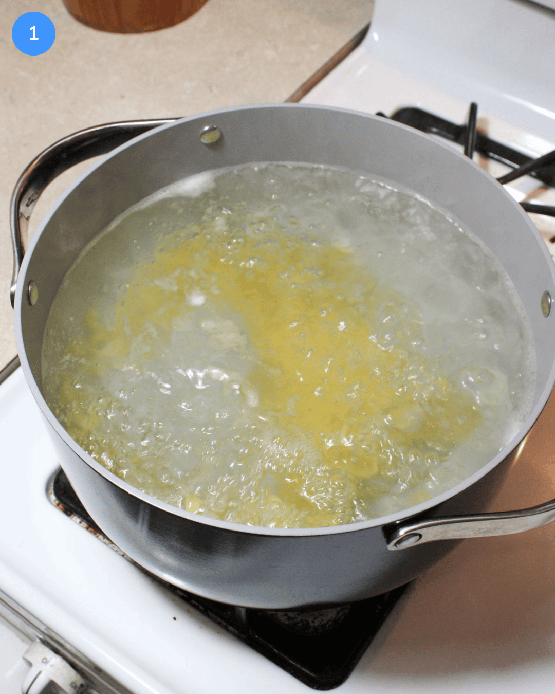 A ceramic pot of pasta boiling on the stove.