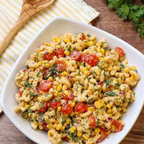 A large white serving dish of freshly made mexican street corn pasta salad.