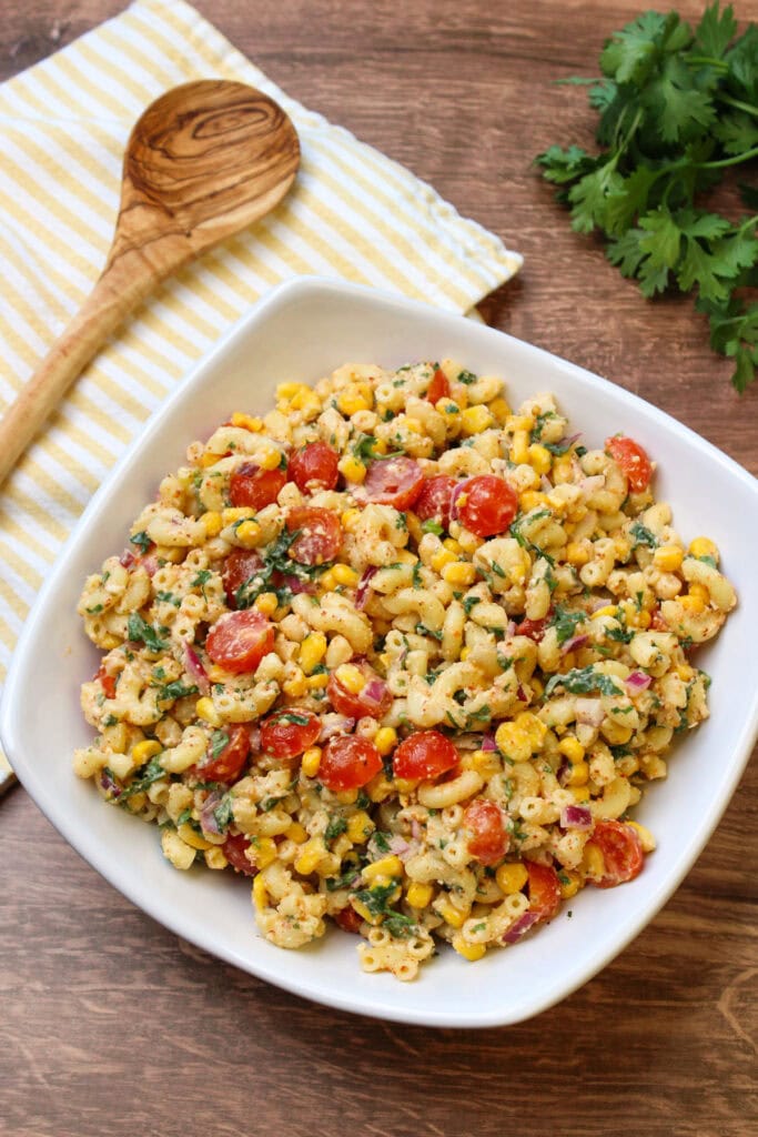 A large white serving dish of freshly made mexican street corn pasta salad.