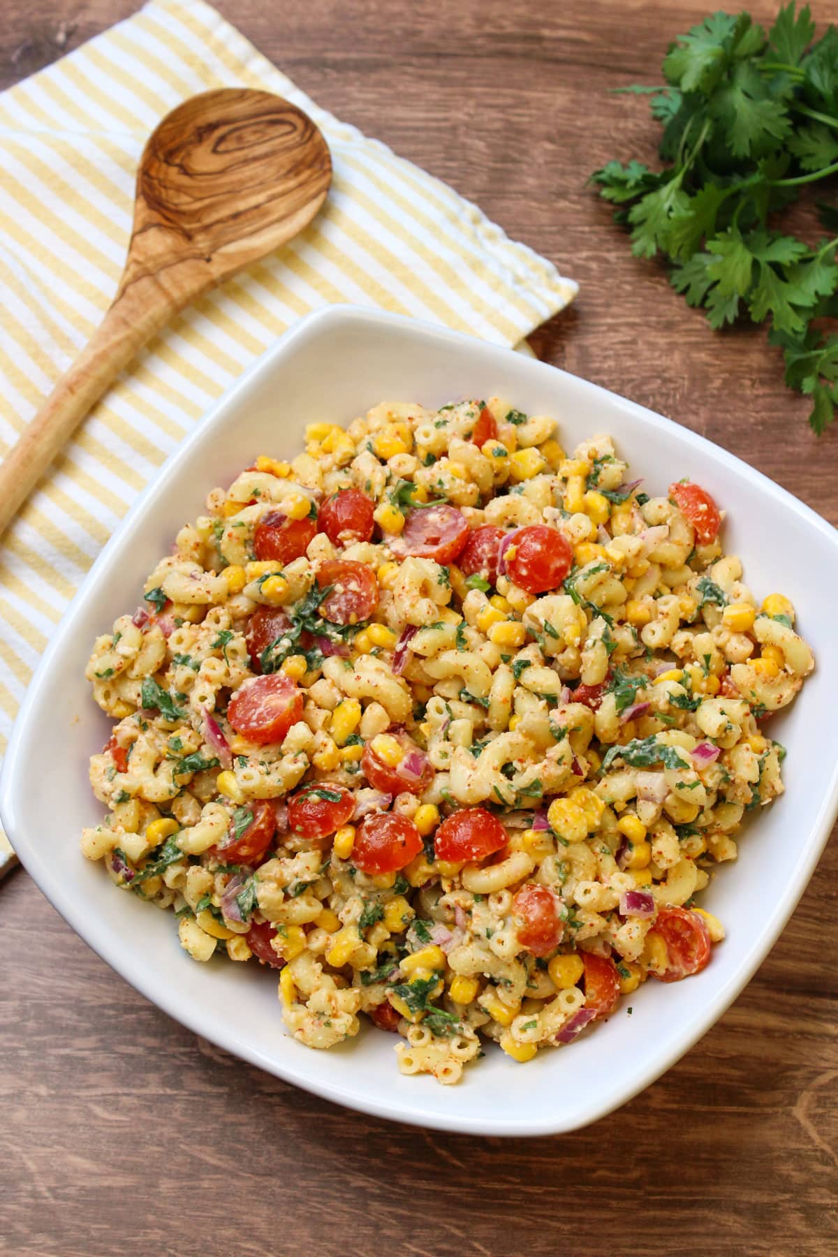 A large white serving dish of freshly made mexican street corn pasta salad.