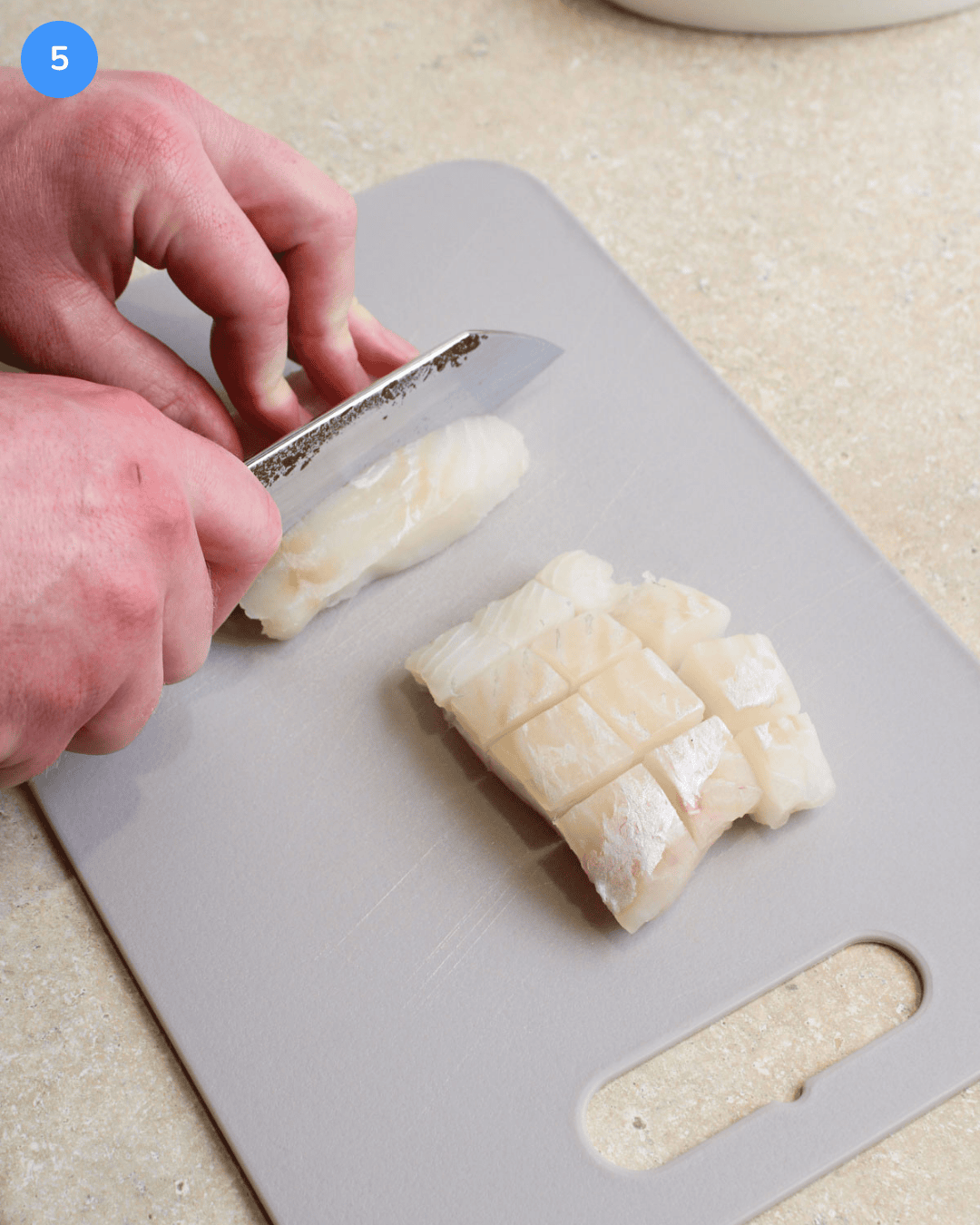 Step 5 of making fried fish tacos. Cod fillets being sliced into one inch cubes.
